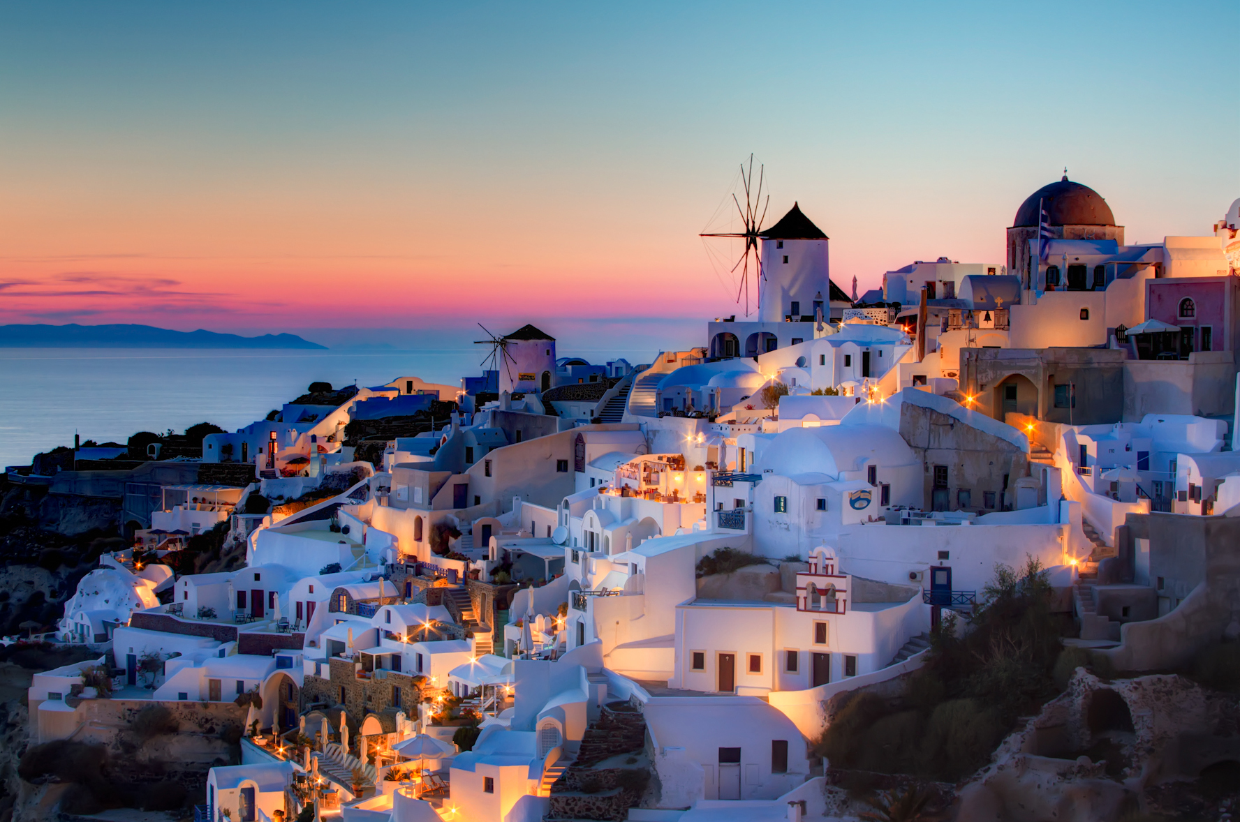 Sunset in Oia, Santorini.

Here is my version of the sunset shot in Oia. This is a blend of 3 shots, 1.3 to 20 seconds, processed as follows:
1) Reduce noice on all 3 raws.
2) Create HRD in Photomatix
3) Blend using Exposure Fusion, sliders set to produce the most natural looking image while still showing some detail in the very dark areas.
4) PS smart sharpen.
5) PS burn the bottom
6) Nik Brilliance and warming
7) Nik Indian summer to warm th elights, masked to not affect the rest.
8) Nik sunlight, brushed over the buildings to add more light
9) Nik Glamour Glow to remove detail in the dark areas.
10) Detailed curves lightening pn windmills.
11) Dodge buildings that were too dark.